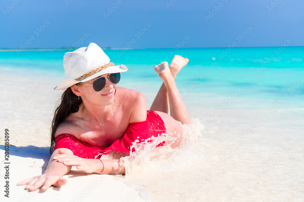 Young beautiful girl lying on snow white tropical beach in shallow water Young beautiful girl lying on snow white tropical beach in shallow water