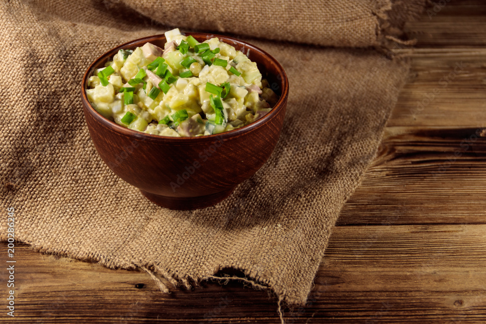 Traditional Russian festive salad Olivier on wooden table