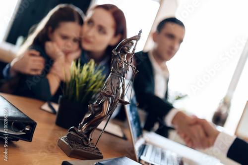 Slika na platnu Bronze statue of Themis stands on table, behind which sits divorcing parents with little girl