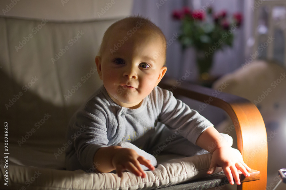 Little baby boy, sitting in rocking chair, looking with curiousity at a night lamp Little baby boy, sitting in rocking chair, looking with curiousity at a night lamp