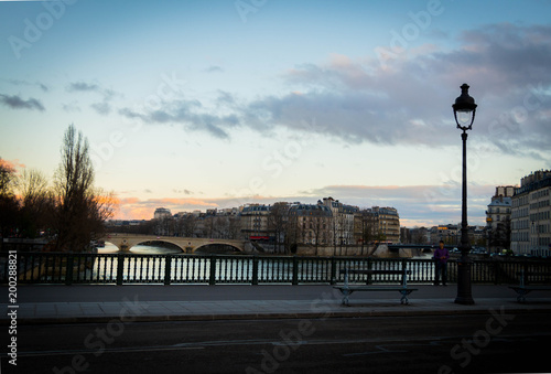 beautiful Parisian bridge against the backdrop of a magically setting sun seen in the early windy spring evening