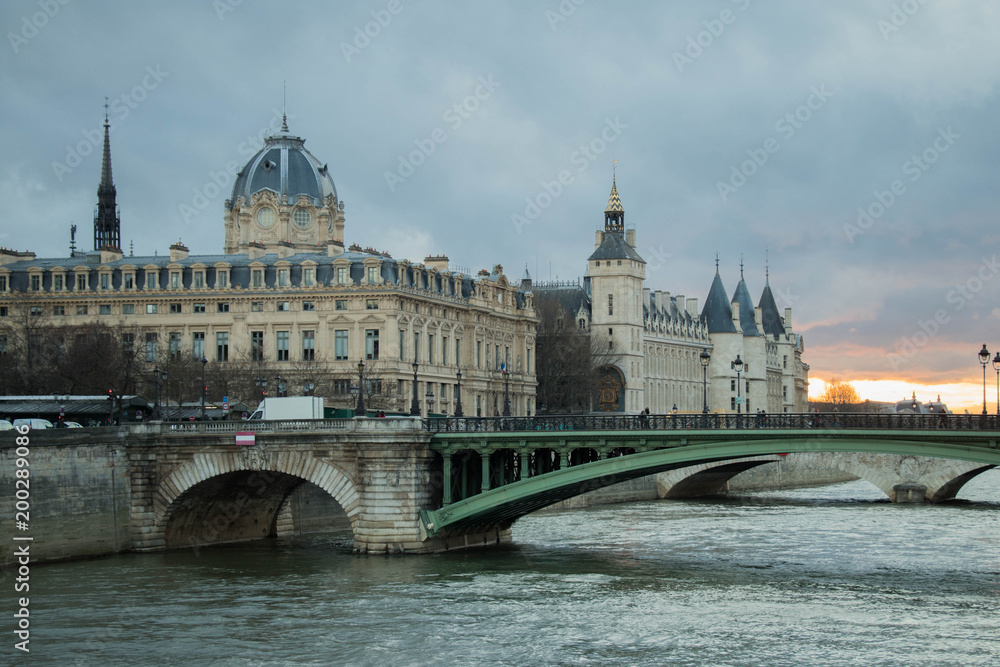 beautiful Parisian bridge against the backdrop of a magically setting sun seen in the early windy spring evening