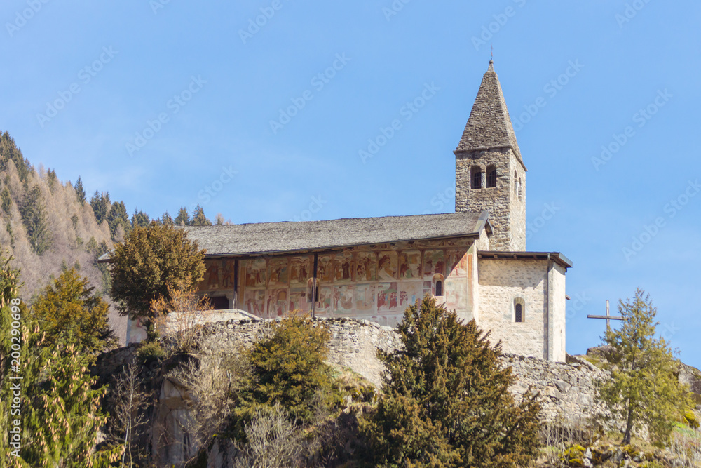 Ancient alpine mountain church of Santo Stefano (St. Stephen) seen on a sunny spring day in Carisolo, Val Rendena, Trentino, Italia