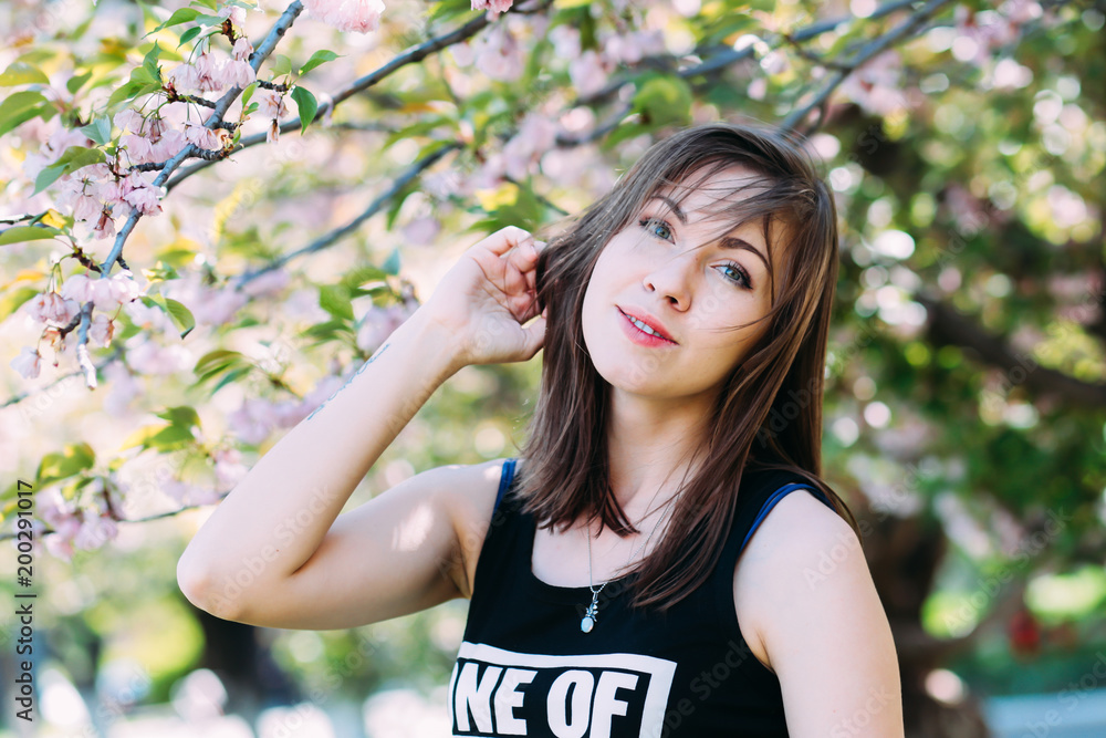 Fototapeta premium Woman near sakura blooming tree. Girl on blooming cherry-tree background. Spring concept