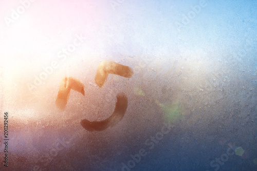 Smiley drawn on the foggy glass on window