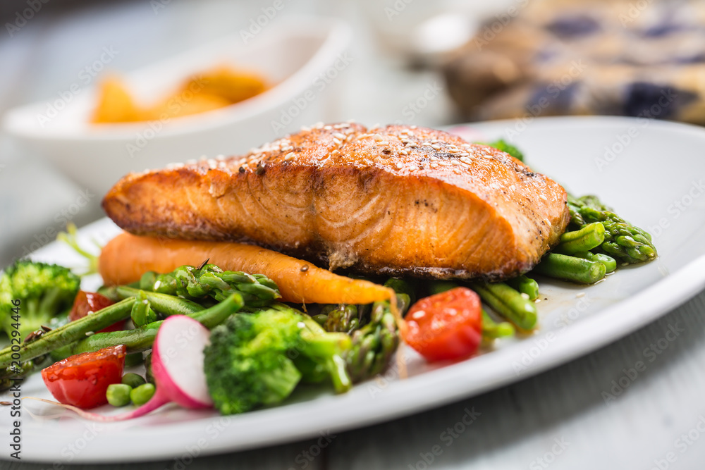 Roasted salmon steak with asparagos broccoli carrot tomatoes radish green beans and peas. Fish meal with fresh vegetable Roasted salmon steak with asparagos broccoli carrot tomatoes radish green beans and peas. Fish meal with fresh vegetable