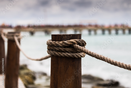 Close-up view of a pole on a rope bridge in Mexico with a port pier in the background