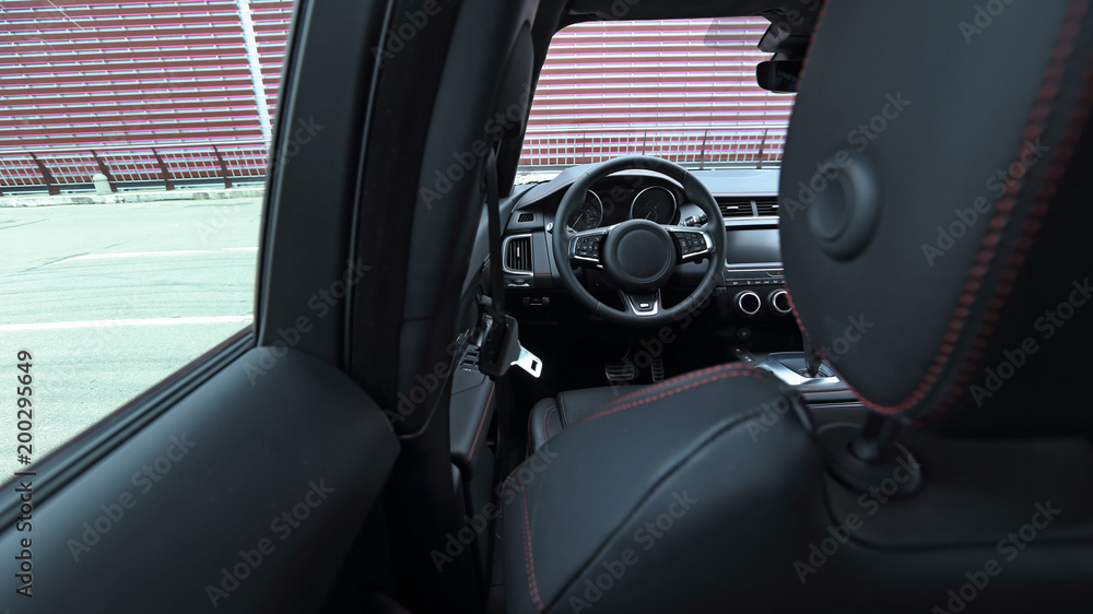 Steering wheel and dashboard in car leather interior. View from behind headrest Steering wheel and dashboard in car leather interior. View from behind headrest