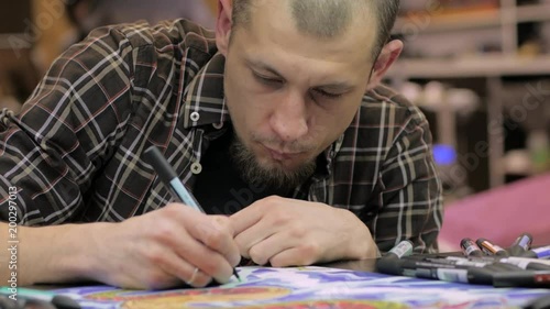 Male painter work with felt-tip pen in studio, tattoer drawing colorful picture photo