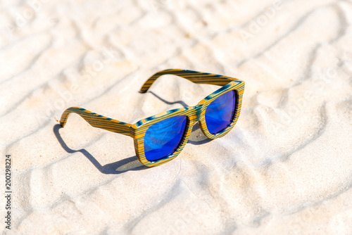 Fashion sunglasses on sandy beach background