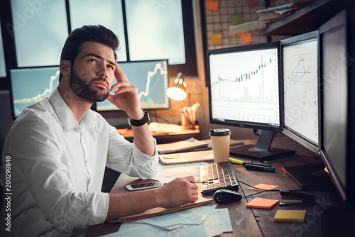 Businessman thinking and using computer of trading graph photo