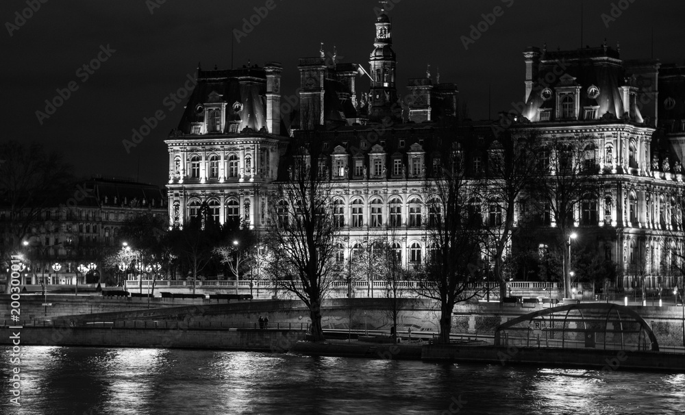  beautifully illuminated at night, an impressive, decorated historic Parisian building reflecting in the Seine