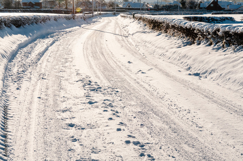 Snow covered rural road with a number of tyre tracks © Stephen
