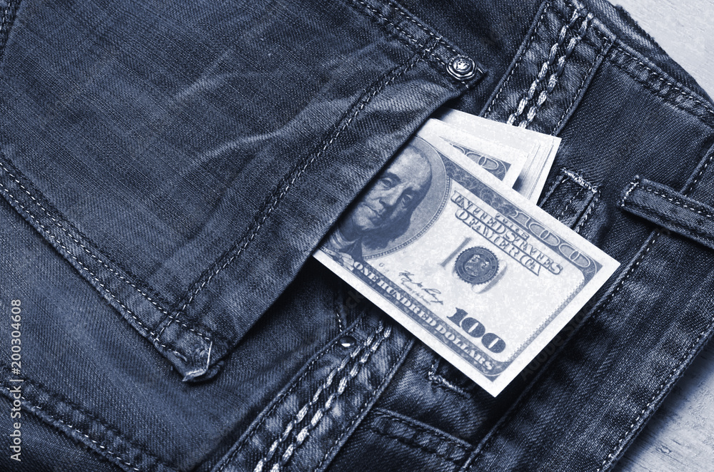 Banknotes of a hundred dollars with a portrait of Franklin peep out of the pocket of jeans trousers. Money in your pocket, cash savings, pocket expenses. The last money, the crisis. Banknotes of a hundred dollars with a portrait of Franklin peep out of the pocket of jeans trousers. Money in your pocket, cash savings, pocket expenses. The last money, the crisis.
