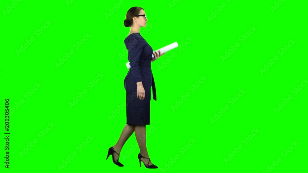 Designer girl comes with a drawing in her hands. Green screen. Side view Designer girl comes with a drawing in her hands. Green screen. Side view