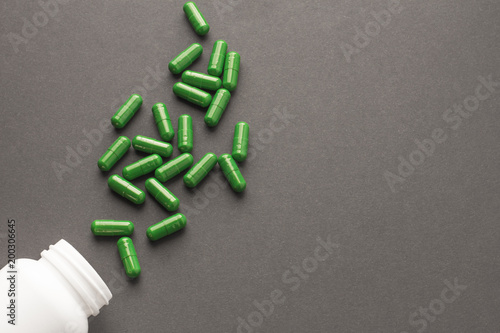Assorted pharmaceutical medicine pills, tablets and capsules and bottle on black background. Copy space for text
