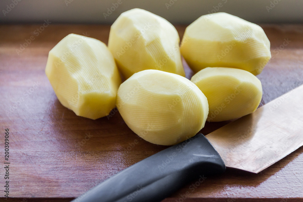 Peeled potatoes on a wooden Board, slicing and cooking fried potatoes
