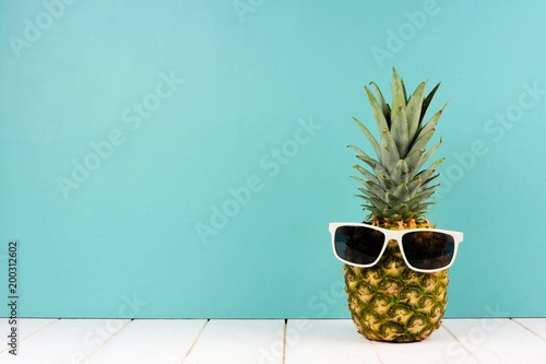 Hipster ananas z modnymi okularami przeciwsłonecznymi na turkusowym tle. Minimalna koncepcja lato.