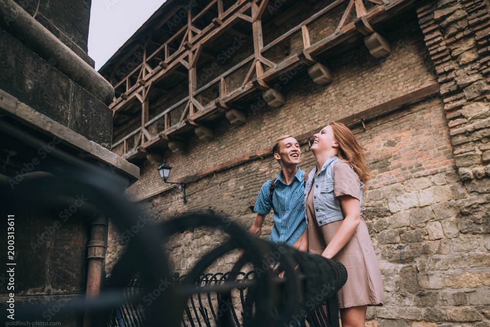 young and beautiful guy and girl standing near brick wall