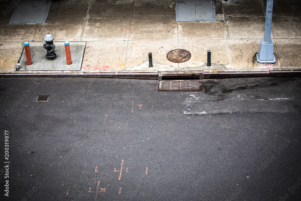 Fototapeta premium Nowy Jork, scena uliczna na Manhattanie widziana z góry z chodnikiem, hydrantem i drenażem włazu widocznym z Chelsea.