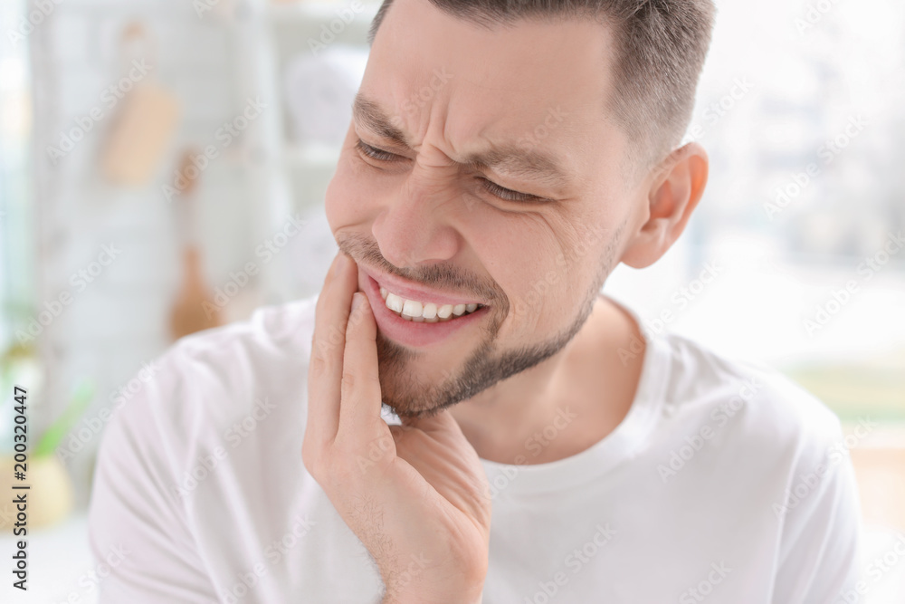 Obraz premium Young man suffering from toothache indoors