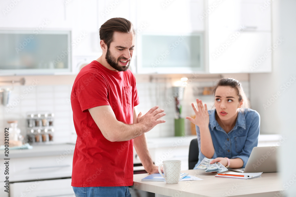 Obraz premium Young couple having argument about family budget in kitchen