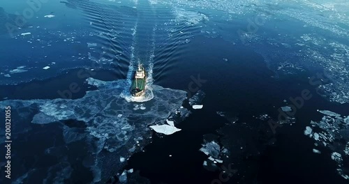 Flying above the Eastern Bosphorus strait. Aerial view of the ship slowly moving through ice floes. Others are stuck on the background. Vladivostok, Russia. Evening