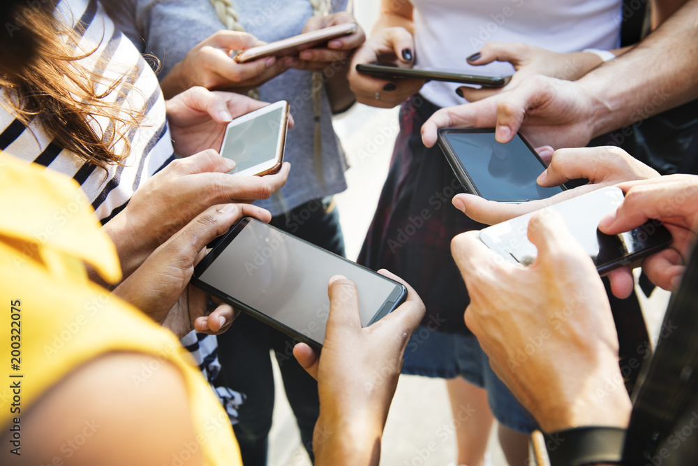 Young adult friends using smartphones together outdoors youth culture concept