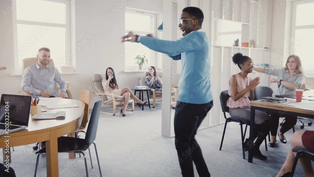 Camera follows African American man enter office doing joyful dance of success, high-fiving multi-ethnic colleagues 4K. Camera follows African American man enter office doing joyful dance of success, high-fiving multi-ethnic colleagues 4K.