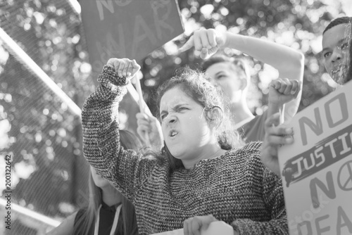 Closeup of angry teen girl protesting demonstration holding posters antiwar justice peace concept photo