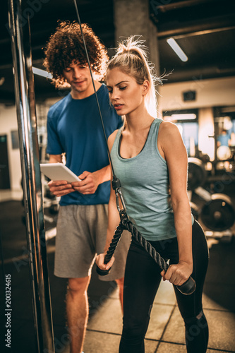 Young beautiful woman doing exercise at the gym with her personal trainer.