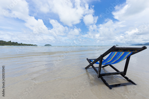 Blue wooden beach chair on the beach with white cloud and blue sky, as for summer season  © soultkd