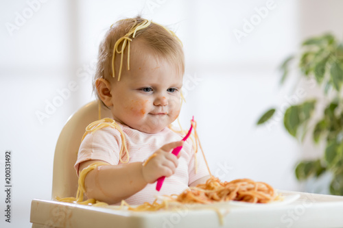 adorable one-year baby toddler try to catch a pasta