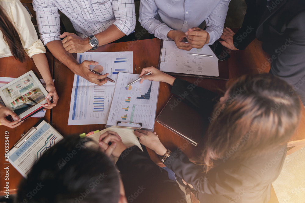 A group of businessmen meet to discuss the situation of marketing in the office and have information sheets on the table. Selected focus. Top view A group of businessmen meet to discuss the situation of marketing in the office and have information sheets on the table. Selected focus. Top view