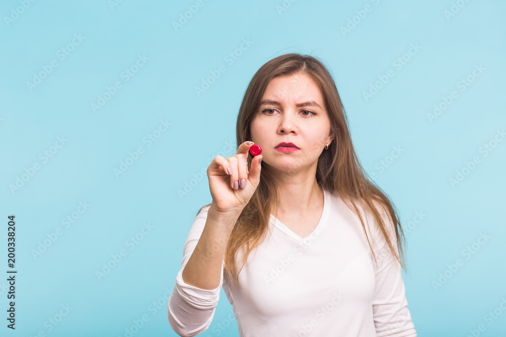 Young woman with red tablet on blue background. Concept of health, diseases and people Young woman with red tablet on blue background. Concept of health, diseases and people
