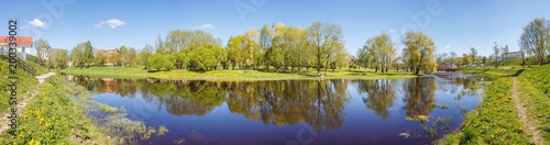 Trees of the park with reflection in the river in Pskov