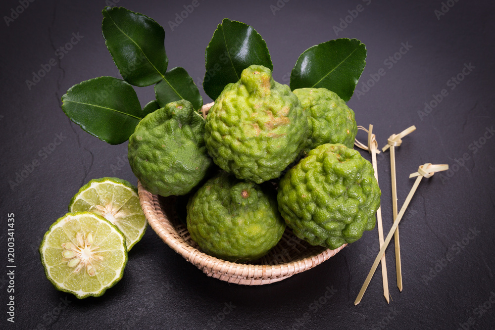 Bergamot, kaffir lime and kaffir lime leaf with basket on dark background Bergamot, kaffir lime and kaffir lime leaf with basket on dark background