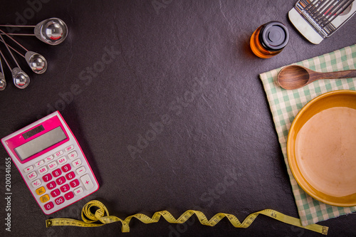 Dieting and nutrition. Diet plan, tape measure, calculator for Count calories,  salad healthy food on black stone background. Weight loss. Copy space.