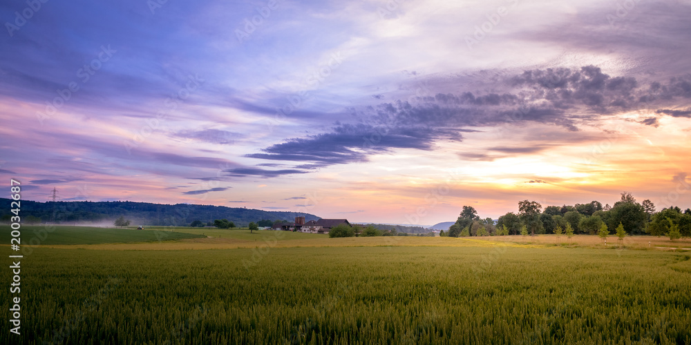 Rural Sunset Landscape of Swiss Farmland With Tractor And Farm-House In Background