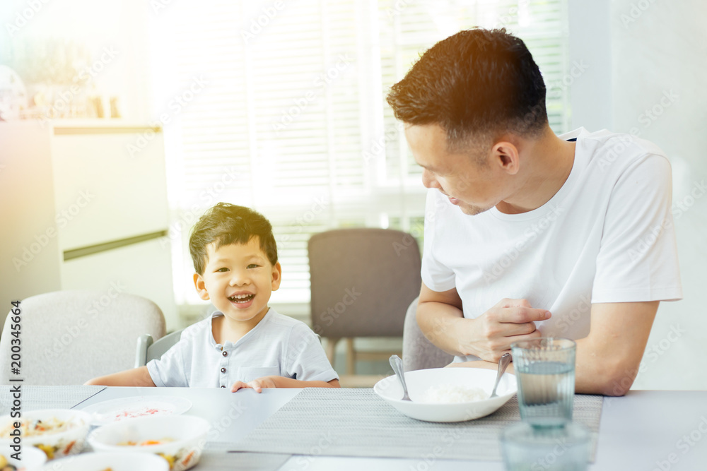 Happy Asian family of father and son playing and laughing while having dinner Happy Asian family of father and son playing and laughing while having dinner