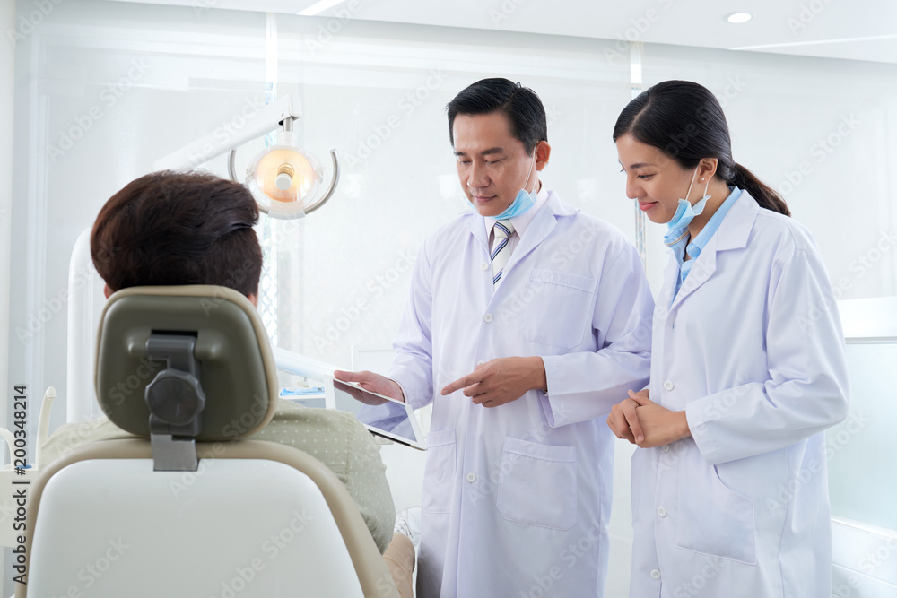 Dentists discussing information on tablet computer Dentists discussing information on tablet computer