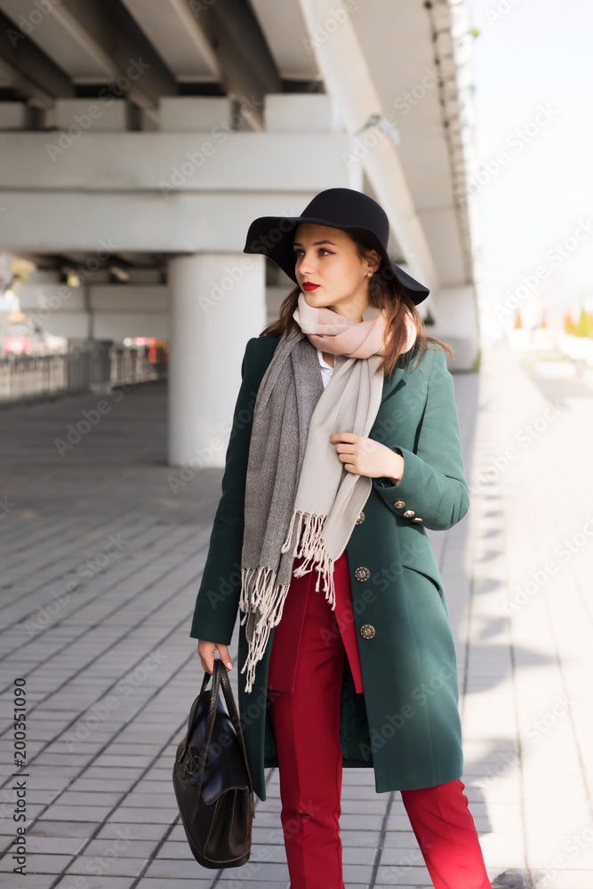 Stylish brunette lady in green coat and black hat posing at the city Stylish brunette lady in green coat and black hat posing at the city