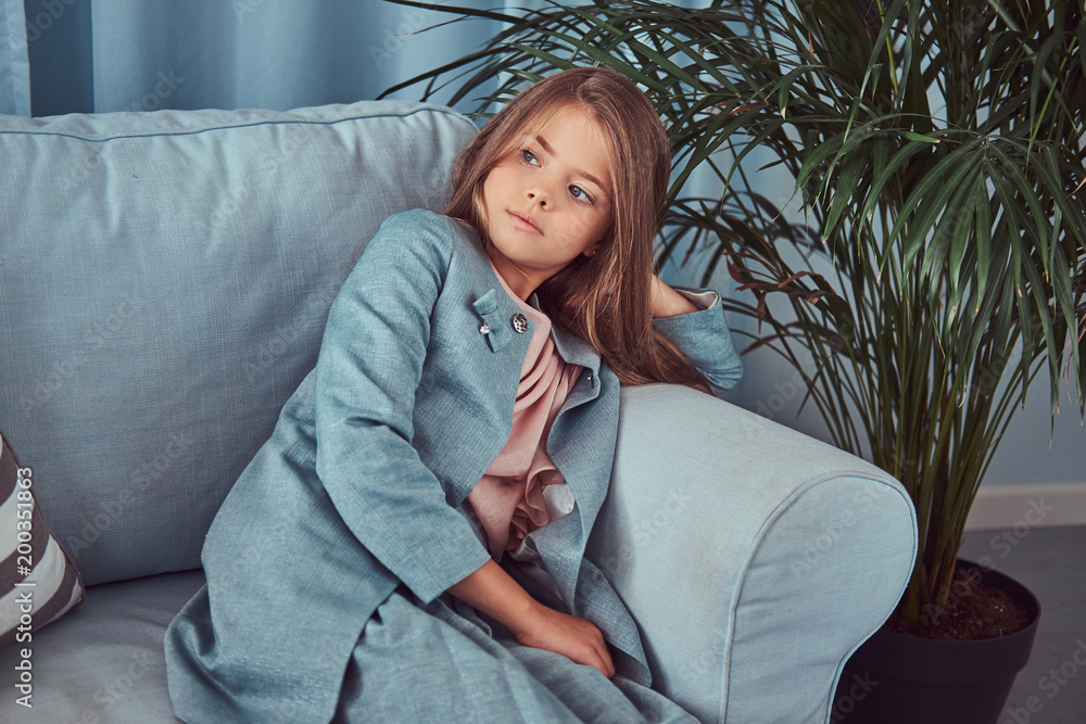 Portrait of a cute little girl wearing a stylish dress, sitting on a