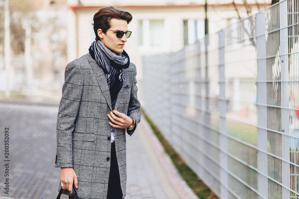 Stylish boy in sunglasses in coat with briefcase on street Stylish boy in sunglasses in coat with briefcase on street