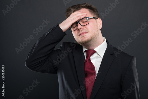 Business man wearing black suit holding head like hurting.