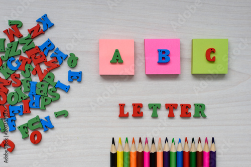 Developing accessories for children's creativity, wooden multicolored letters of the alphabet , lettering letter and ABC, eraser, colored pencils on a wooden background