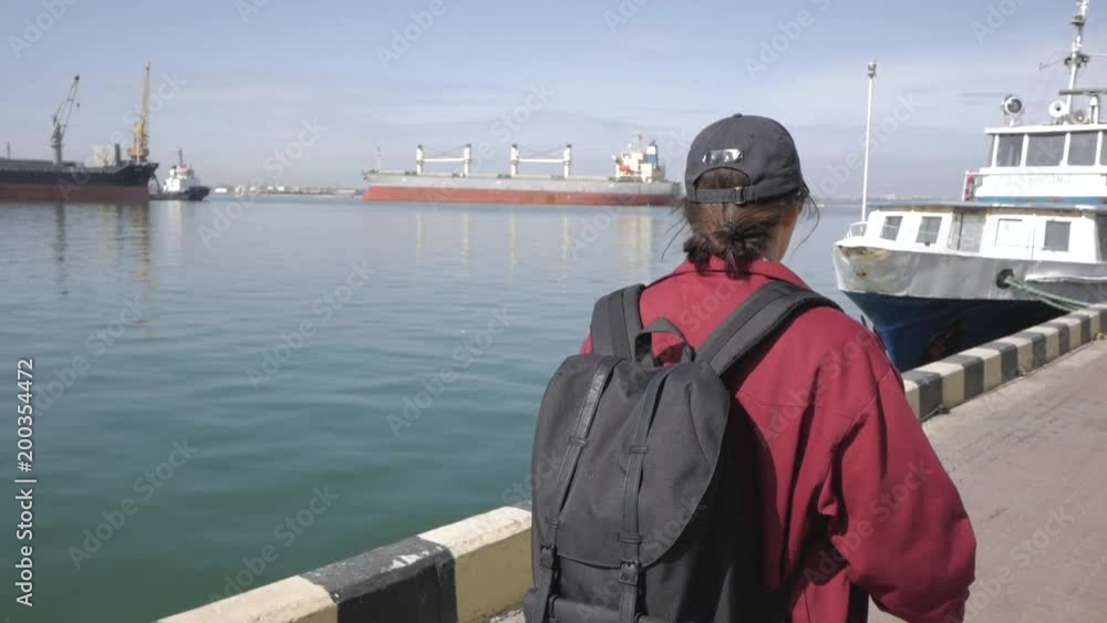 Young man traveler walking near the sea port, tourist having good time, harbor background Young man traveler walking near the sea port, tourist having good time, harbor background