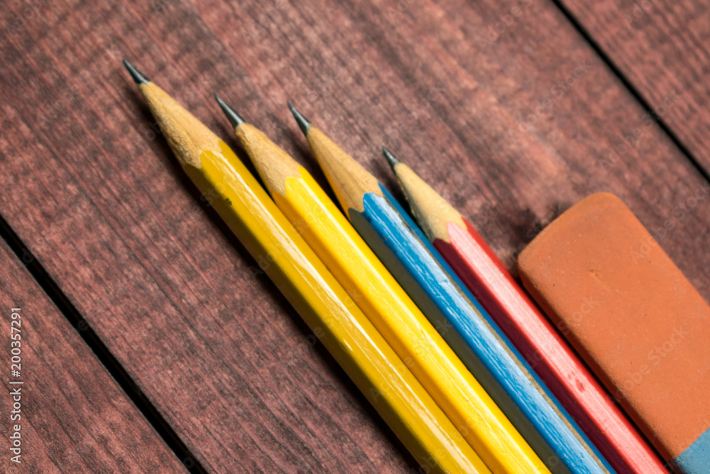 Naklejka premium Bright colorful pencils next to a blank sheet of paper. School supplies stationery on a wooden texture table. Trendy minimalism. Concept back to school. Top view