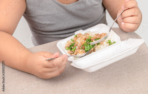 Obese fat boy eating fried rice in foam box © kwanchaichaiudom