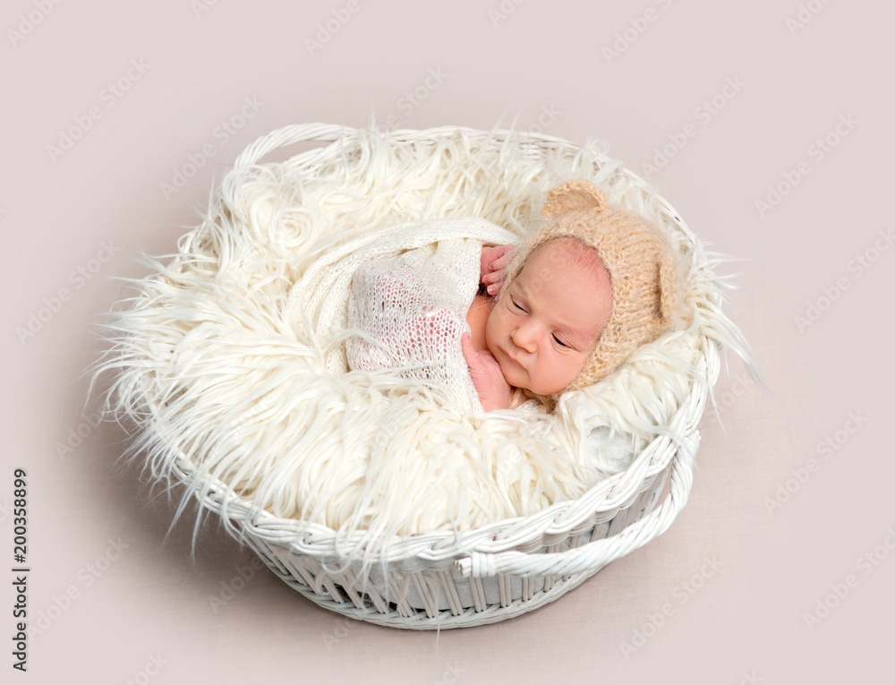 Newborn baby in funny bonnet napping in basket Newborn baby in funny bonnet napping in basket